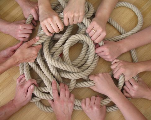 Gruppe von Händen, die gemeinsam ein dickes Seil halten, symbolisiert Zusammenarbeit und Teamarbeit.