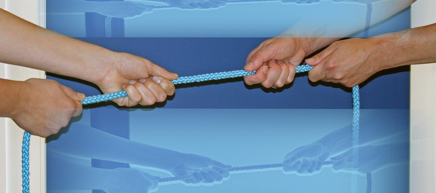 Zwei Hände umschließen ein Seil, das vor einem blauen Hintergrund sichtbar